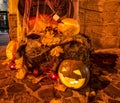 Halloween decorations - Jack-o'-lanterns - carved pumpkins, burning candles, hay bale, fallen maple leaves