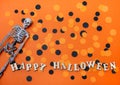Halloween decorations on an orange background. Skeleton and confetti, Happy halloween inscription