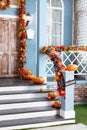 House entrance staircase decorated for autumn holidays, fall flowers and pumpkins. Cozy wooden porch of the house with pumpkins Royalty Free Stock Photo