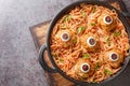 Halloween dinner of meatballs with monster eyes and pasta with tomato sauce in a frying pan close-up. Horizontal top view Royalty Free Stock Photo