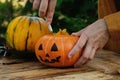 Halloween DIY jack o lantern. Woman carves Halloween pumpkin in back yard.