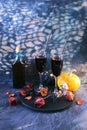 Halloween drinks, wine, pumpkins, mystical decorations, dry roses and shadows on a black background