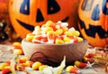 Halloween festive composition with sweet corn in bowl and smiling pumpkins guards, lantern, straw and fallen leaves on dark Royalty Free Stock Photo