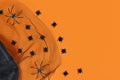 Halloween flat lay with mesh, fake spiders and confetti in shape of small spiders on orange background with copy space