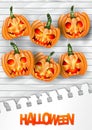 Halloween flyer or poster with hanging pumpkin creepy faces over white paint wooden board plank background.