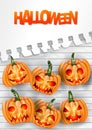 Halloween flyer or poster with pumpkins with creepy faces over white paint wooden board wall and torn out sheet of paper.