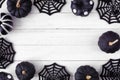 Halloween frame of black and white patterned pumpkins and spider web decor on a white wood background