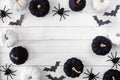 Halloween frame of black and white pumpkins with bats and spiders over a white wood banner background