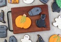 Halloween gingerbreads, pumpkin, tombstone, black cat on a board over wooden table Royalty Free Stock Photo