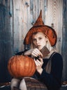 Halloween girl. Attractive witch holding pumpkin and knife for a `trick or treat`. Woman dressing in Halloween costume Royalty Free Stock Photo