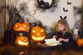 Halloween girl reads book spells. Blonde witch. Magic wand in hands of magician.