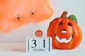 Halloween greeting card. Calendar dated October 31, spider web and Jack-o-latern on white table. Selective focus