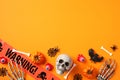 Halloween greeting card design. Flat lay, top view skull, spider webs, pumpkins, skeleton hands, warning tape on orange background Royalty Free Stock Photo