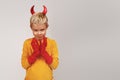 Halloween Happy child laughs out loud with devilish horns in a yellow turtleneck against a gray studio