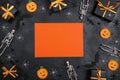 Halloween holiday background with blank orange card surrounded by gifts and decorations on black backdrop Royalty Free Stock Photo