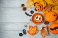 Halloween holiday background with coffee cup, pumpkin and autumn leaves on wooden table. Top view from above. Flat lay