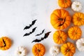 Halloween holiday card with party decorations of pumpkins and bats on white stone table top view. Happy halloween greeting poster Royalty Free Stock Photo