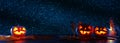 Halloween holiday concept banner. Pumpkins over wooden table at night scary, haunted and misty forest.