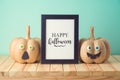 Halloween holiday concept with cute funny pumpkin decor and photo frame on wooden table Royalty Free Stock Photo