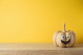 Halloween holiday concept with cute funny pumpkin decor on wooden table over yellow background Royalty Free Stock Photo