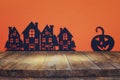 Halloween holiday concept. Empty rustic table in front of black houses village and pumpkin background. Ready for product display m Royalty Free Stock Photo