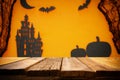 Halloween holiday concept. Empty rustic table in front of spider web, Pumpkins, witch house and bats background Royalty Free Stock Photo