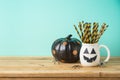 Halloween holiday concept with jack o lantern cup and black pumpkin decor on wooden table Royalty Free Stock Photo