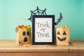 Halloween holiday concept with picture frame, party gift paper bags decor and candy on wooden table