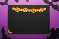 Halloween holiday concept top view. Black spiders, bats, ghost, orange paper Jack O`Lantern, pumpkins on the perple background. Royalty Free Stock Photo