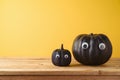 Halloween holiday creative concept with cute funny black pumpkin decor on wooden table over yellow background Royalty Free Stock Photo