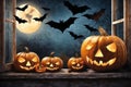 halloween holiday decorations, scary jack o lantern pumpkins and candles on a windowsill, flying bats outside the window Royalty Free Stock Photo