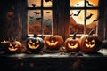 halloween holiday decorations, scary jack o lantern pumpkins and candles on a windowsill, flying bats outside the window Royalty Free Stock Photo