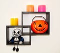 Halloween home accessories, a pumpkin with sweets and a ghostly monster doll on a designer shelf are hanging on the wall.