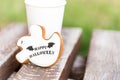 Halloween homemade gingerbread and honey cookies as a white ghost with happy halloween greetings text on a wooden bench and cup