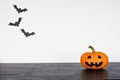 Halloween jack o lantern on a black shelf against a white wall with bats Royalty Free Stock Photo