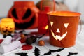 Halloween jack o lantern bucket, glowing candle, festive candy, skulls, black bats, ghost, spider decorations on white wooden