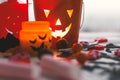 Halloween jack o lantern bucket, glowing candle, festive candy, skulls, black bats, ghost, spider decorations on white wooden