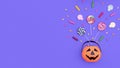 Halloween Jack o Lantern pail with bottom border of spilling candy over purple background with copy space.