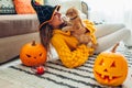 Halloween jack-o-lantern pumpkins. Woman in hat playing with cat lying on carpet decorated with pumpkins and candles Royalty Free Stock Photo
