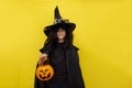 Halloween kid holds candy bowl in his hand jack o lantern and waiting for sweets. Child in black sorcerer's costume Royalty Free Stock Photo