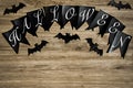 Halloween lettering on black flags. Nearby are figures of bats. On a wooden background.