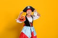 Halloween. Little child in a carnival costume of a pirate on a yellow background. Little girl holding an alarm clock Royalty Free Stock Photo