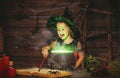 Halloween. little witch child cooking potion in cauldron with Royalty Free Stock Photo