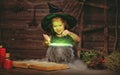 Halloween. little witch child cooking potion in cauldron with Royalty Free Stock Photo