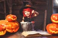 Halloween. little witch child cooking potion with pumpkin and Royalty Free Stock Photo