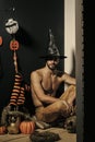 Halloween macho in witch hat and bared torso sitting