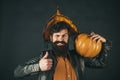 Halloween Man posing with pumpkins. Scary hipster man with beard in Halloween hat. Halloween man with pumpkin - Holidays