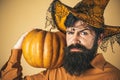 Halloween man with pumpkin - Holidays celebration concept. Scary hipster man with beard in Halloween hat. Bearded