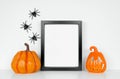 Halloween mock up black frame with pumpkin and jack o lantern decor on a white shelf Royalty Free Stock Photo