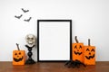 Halloween mock up black frame on a wood shelf with wood jack o lantern decor, spiders and skull